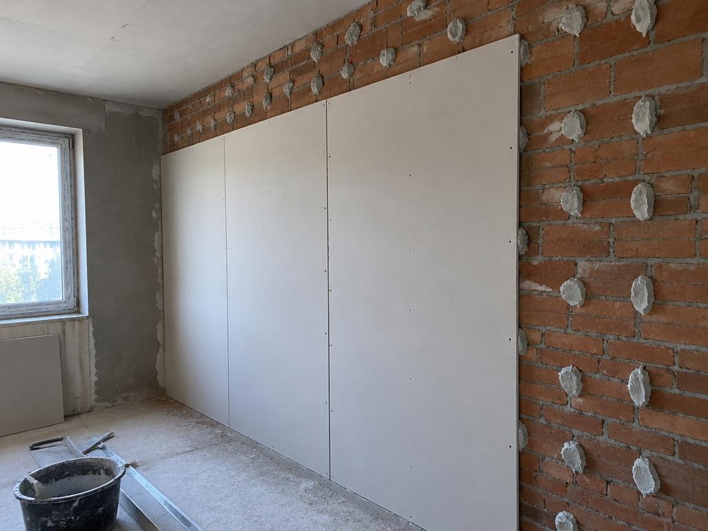 Plasterboard fixed to a brick wall using adhesive dabs
