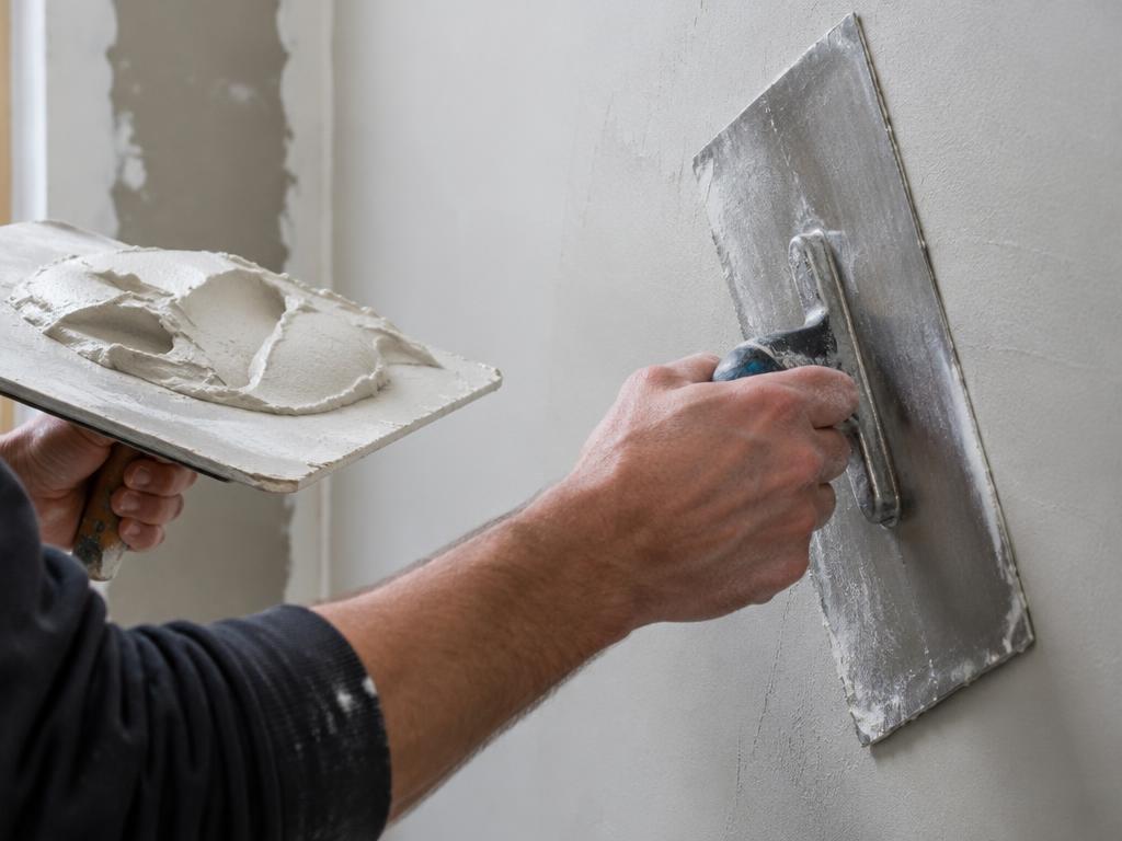 Trowel smoothing a fresh skim coat on a wall